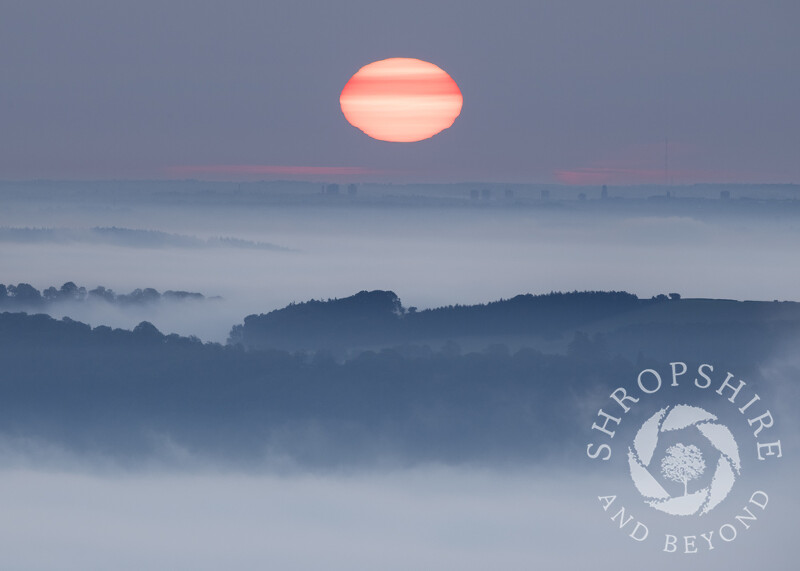 The sun rising over Wolverhampton, seen from Caradoc, Shropshire, with Wenlock Edge.