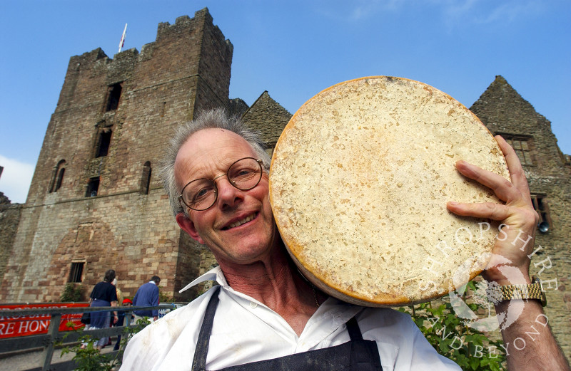 A vendor holds a cheese wheel in the grounds of Ludlow Castle during Ludlow Food Festival, Shropshire, England.
