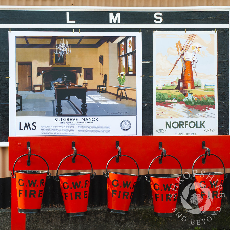 Fire buckets and vintage advertising signs on the platform at Hampton Loade station, Severn Valley Railway, Shropshire, England.