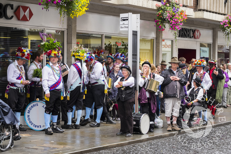 Morris dancers wait for a bus in Shrewsbury town centre, Shropshire.