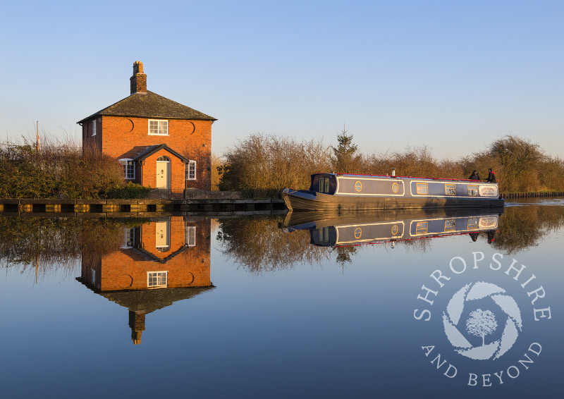 A canal boat passes a house on the Llangollen branch of the Shropshire Union Canal at Whixall, Shropshire.