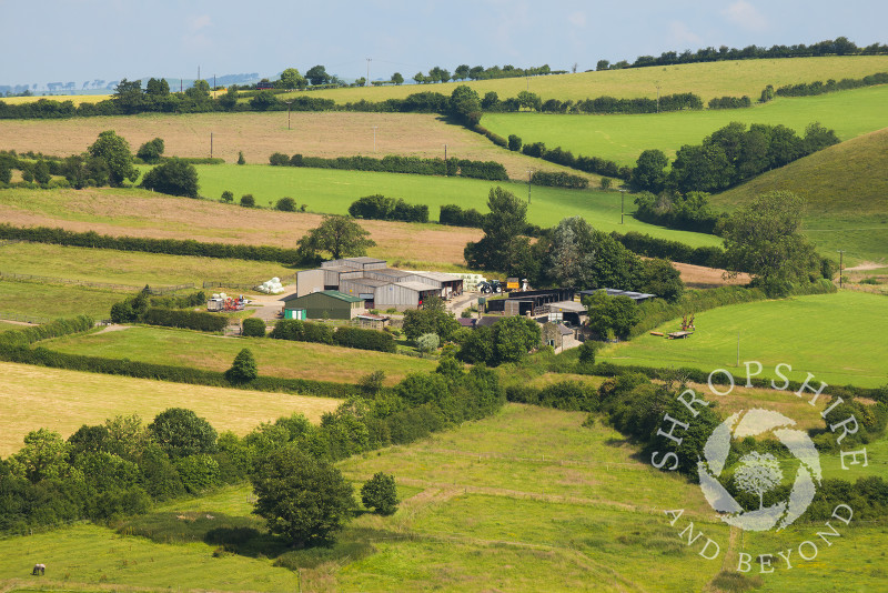A farm nestles amid rolling countryside near Hopesay, Craven Arms, Shropshire, England. 