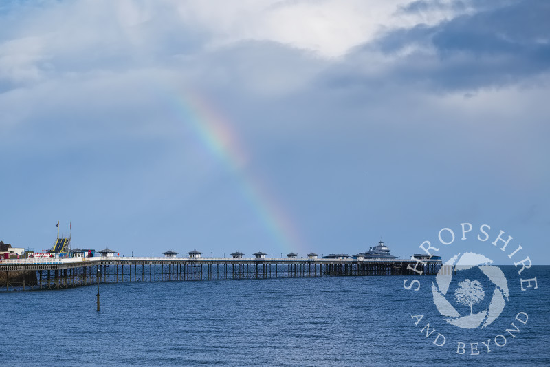 Rainbow and rain clouds over the pier at Llandudno, Conwy, Wales.