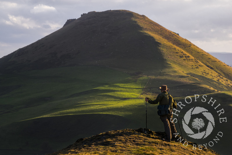 A walker enjoys the view of Caer Caradoc seen from the Lawley, Shropshire.