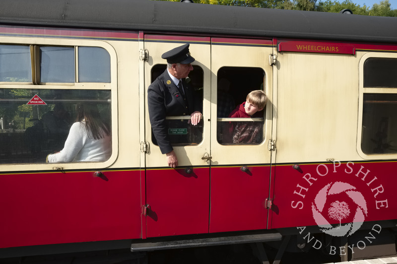 Guard and young passenger looking out of carriage windows at Highley Station, Shropshire, on the Severn Valley Railway heritage line.