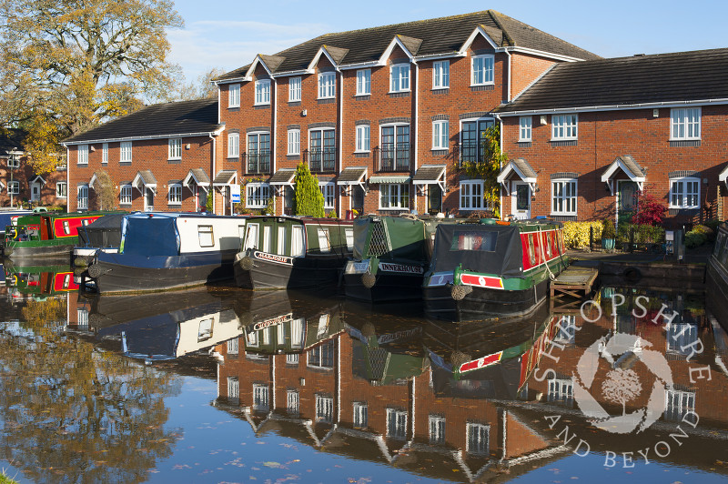 Canal boats and homes reflected in the Shropshire Union Canal at Market Drayton, Shropshire, England.