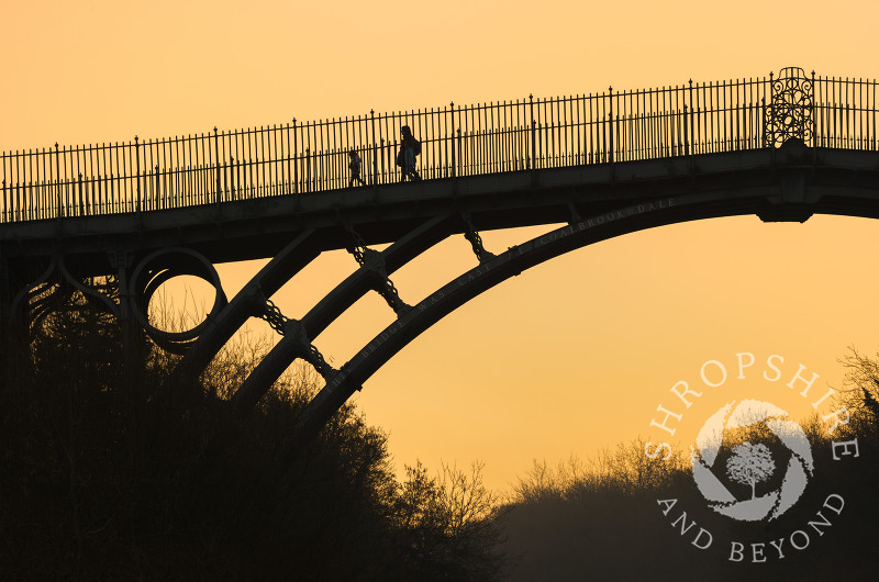 Walkers at sunrise on the Iron Bridge at Ironbridge, Shropshire.