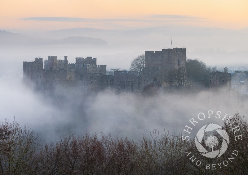Ludlow Castle emerges from the mist at dawn in Shropshire.