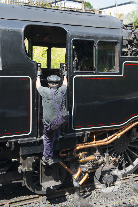 Engineer climbing aboard a steam locomotive at Llangollen Railway Station, Dengishshire, Wales.
