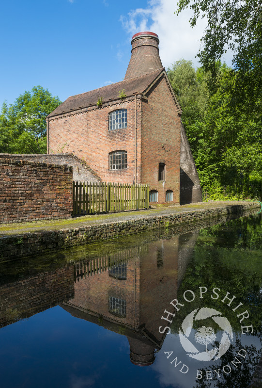 The Coalport China Museum, one of the Ironbridge Gorge Museums, reflected in the water of the Shropshire Canal at Coalport, Shropshire.