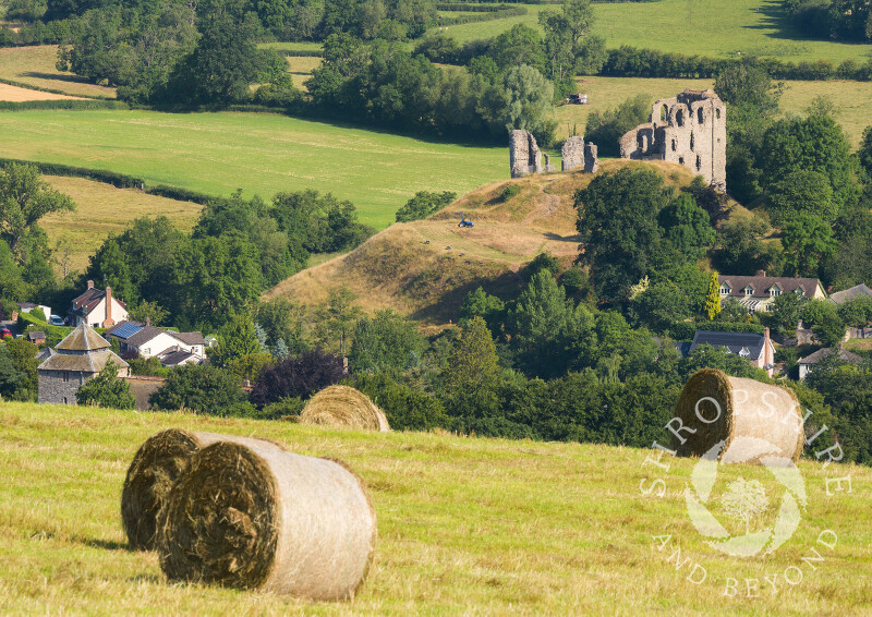 Hay bales in a field overlooking Clun and its castle, Shropshire.