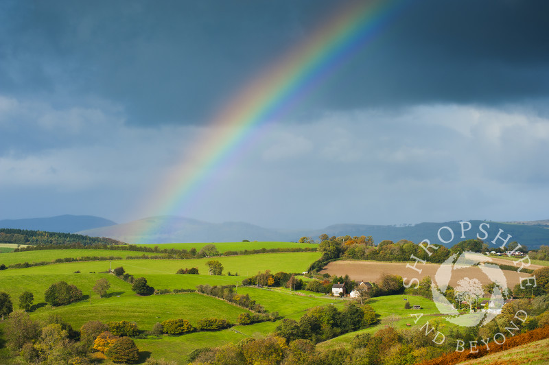 Autumn rainbow over Round Oak, seen from Hopesay Common, near Craven Arms, Shropshire, England.