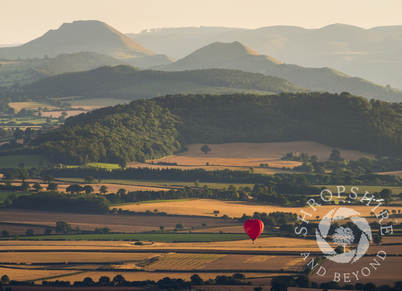 A hot air balloon over Shropshire, seen from the Wrekin, with the Stretton Hills in the distance.
