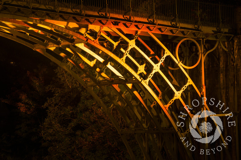 The illuminated cast iron structure of the Iron Bridge at Ironbridge, Shropshire, England. 
