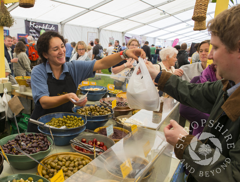 A shopper buys olives at the Olive Press stall, 2014 Ludlow Food Festival, Shropshire, England.