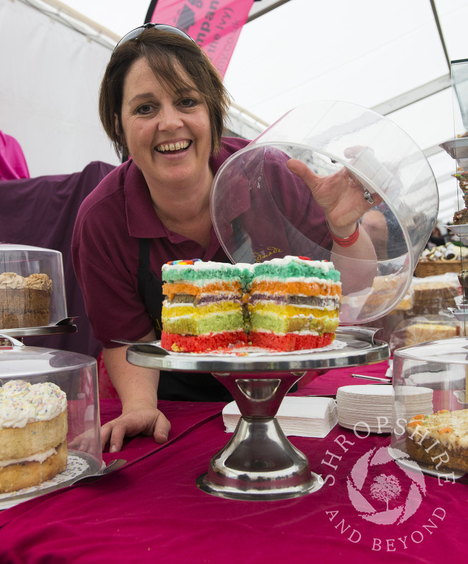 Louise Gough of Handmade In Ludlow showing off a colourful rainbow cake at Ludlow Food Festival, Shropshire.