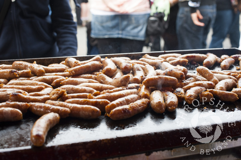 Sausages sizzle on a griddle as part of the Sausage Trail at Ludlow Food Festival, Shropshire, England.