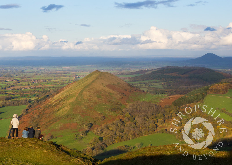 A family enjoy a view of the Lawley and the Wrekin from Caer Caradoc, Church Stretton, Shropshire.
