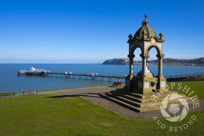 Victorian drinking fountain in Happy Valley Gardens looking to Llandudno Pier, North Wales.