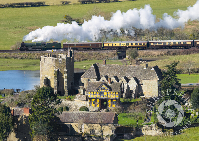 Steam locomotive 7029 Clun Castle passes Stokesay Castle in Shropshire.