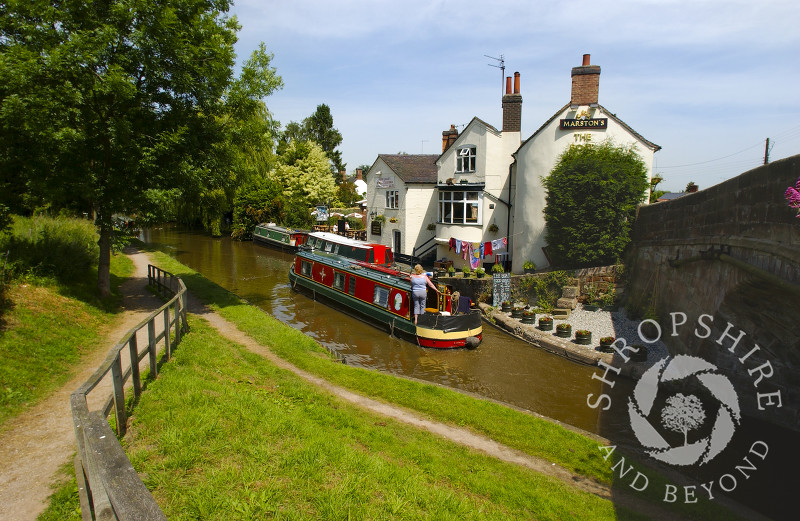 A narrowboat passes the Boat Inn at Gnosall on the Shropshire Union Canal, Staffordshire, England.
