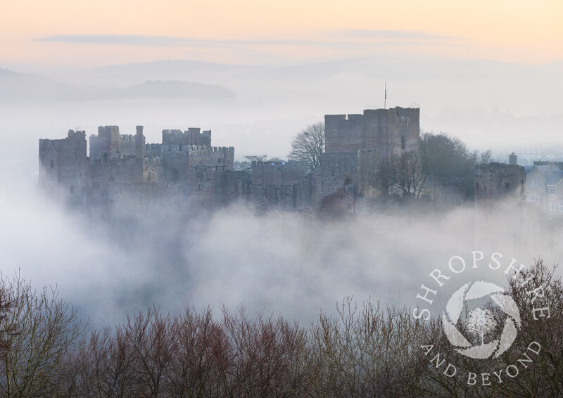 Ludlow Castle emerges from the mist at dawn in Shropshire.