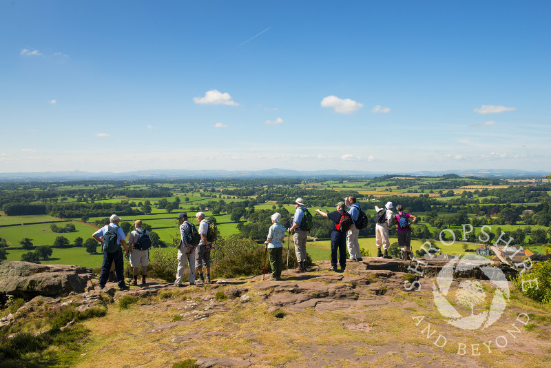 A group of walkers look out over the north Shropshire landscape from Grinshill Hill, Shropshire, England.