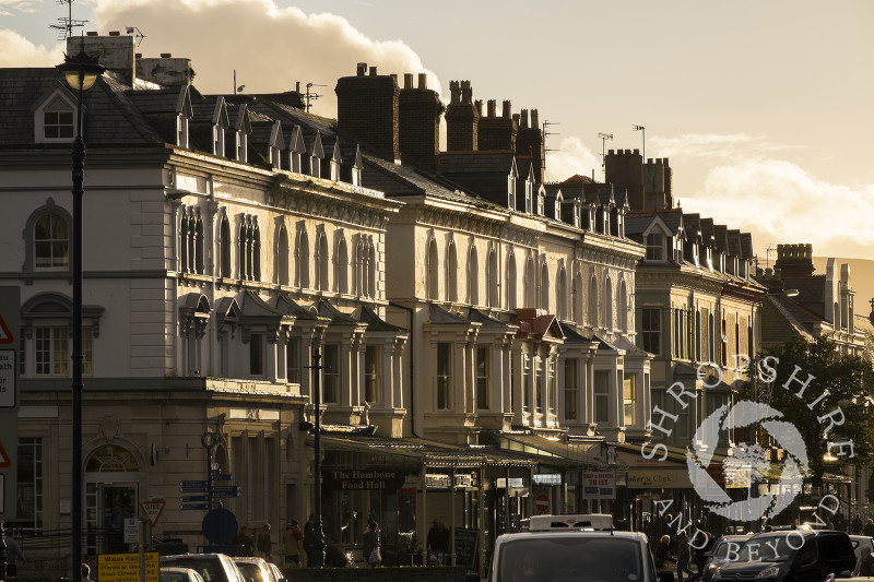 Sunlight picks out buildings and shops in Lloyd Street, Llandudno, Conwy, Wales.