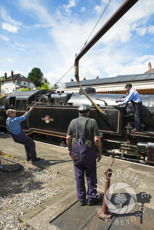 A steam locomotive taking on water at Llangollen station, Denbighshire, Wales.