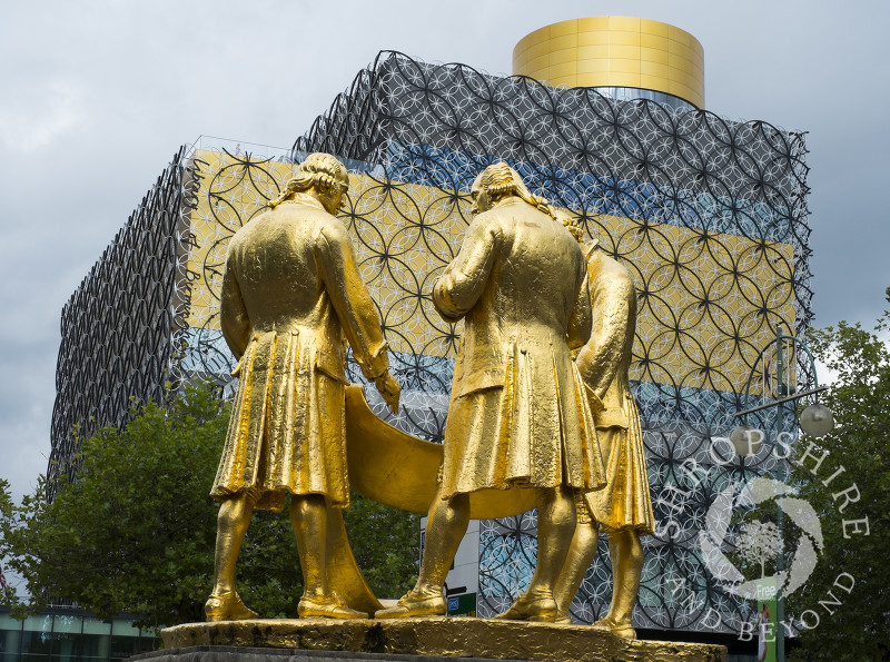 The bronze statue of Matthew Boulton, James Watt and William Murdoch in front of the Library of Birmingham, England, UK. The statue is known locally as the Golden Boys.