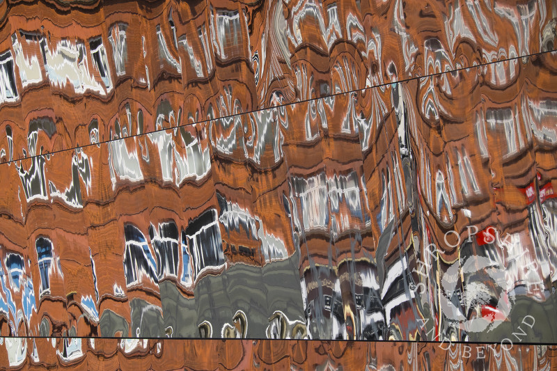 City centre buildings reflected in the outer wall of the Grand Central shopping centre, Birmingham, West Midlands.