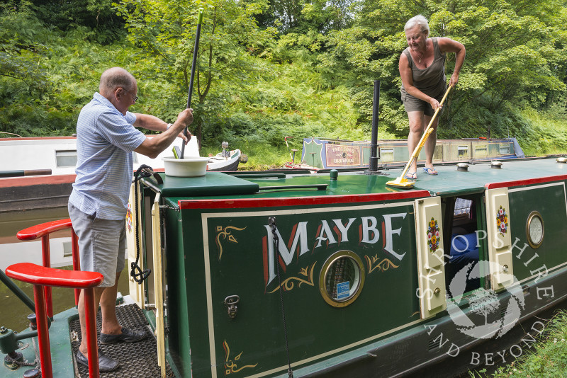 People cleaning a canal boat on the Shropshire Union Canal at Brewood, Staffordshire, England.