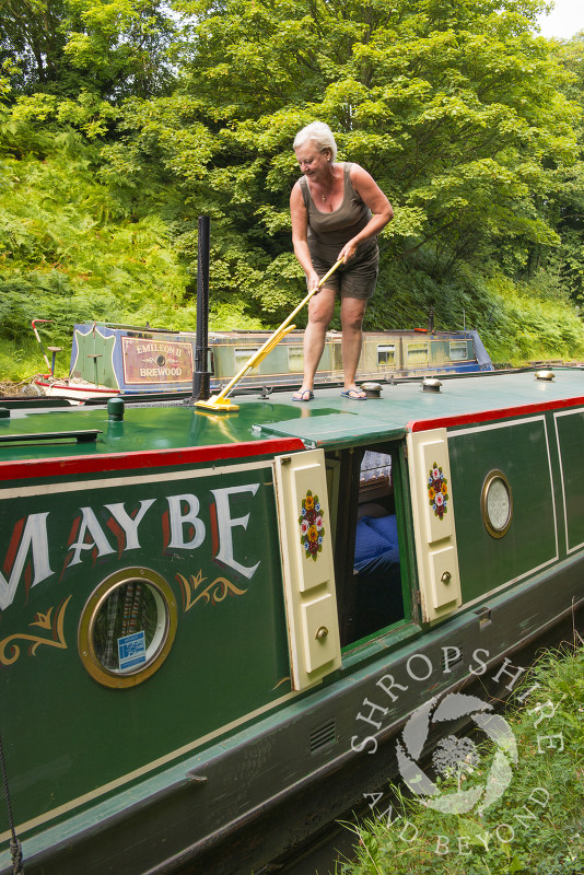 Cleaning a canal boat on the Shropshire Union Canal at Brewood, Staffordshire, England.