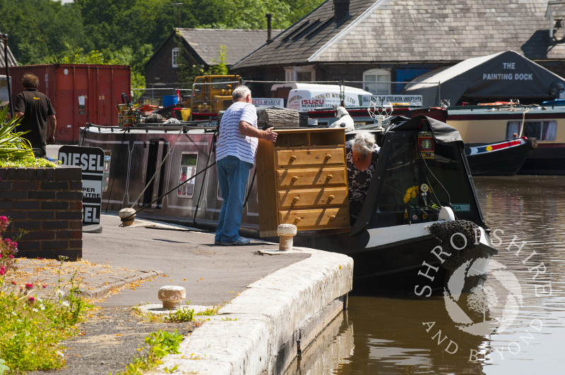 Loading a chest of drawers onto a canal boat at Norbury Junction on the Shropshire Union Canal, Staffordshire, England.