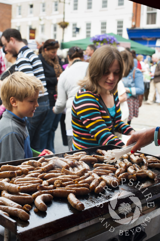 Sausages sizzle on a griddle as part of the Sausage Trail at Ludlow Food Festival, Shropshire, England.