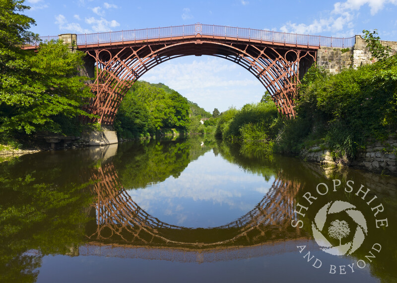 The Iron Bridge reflected in the River Severn at Ironbridge, Shropshire.