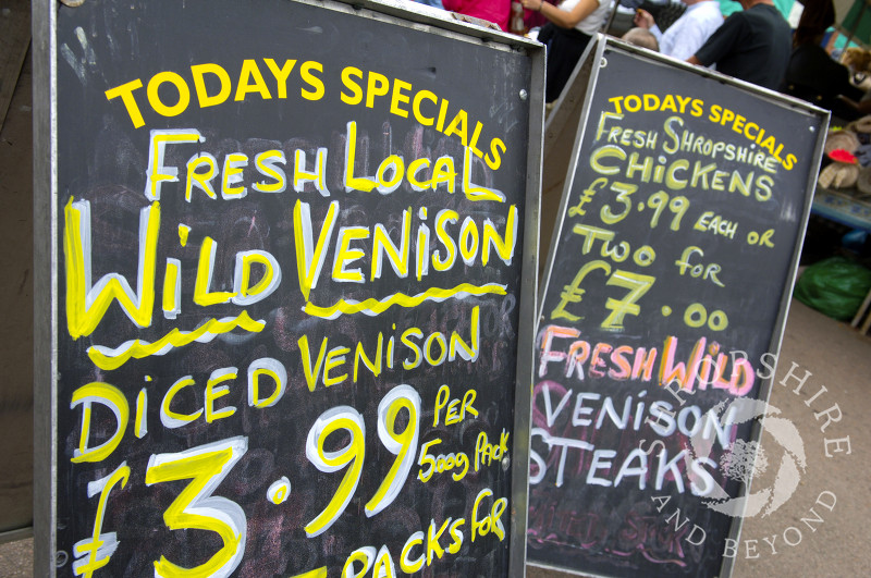 Boards advertising meat and poultry for sale in the street market during Ludlow Food Festival, Shropshire, England.