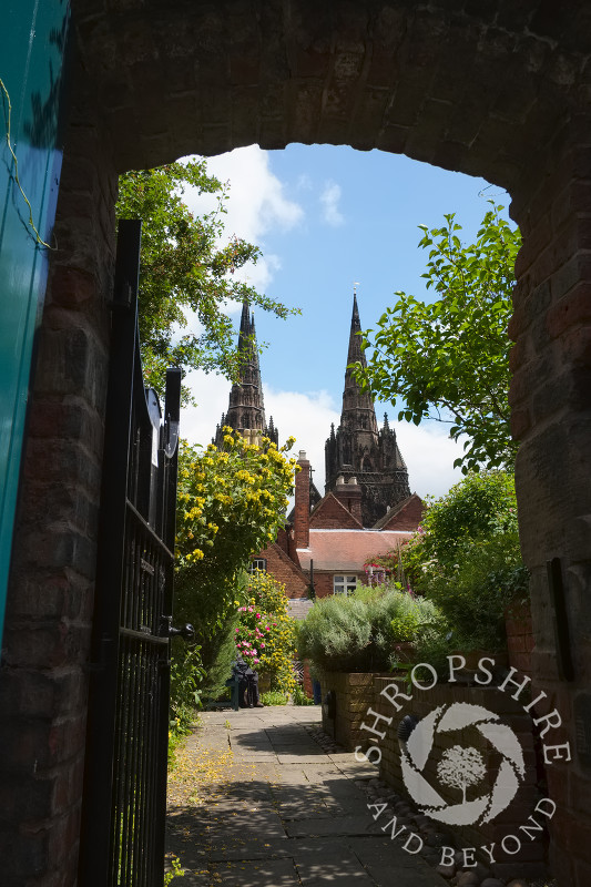 Lichfield Cathedral seen through a gateway at Erasmus Darwin House in Lichfield, Staffordshire, England.