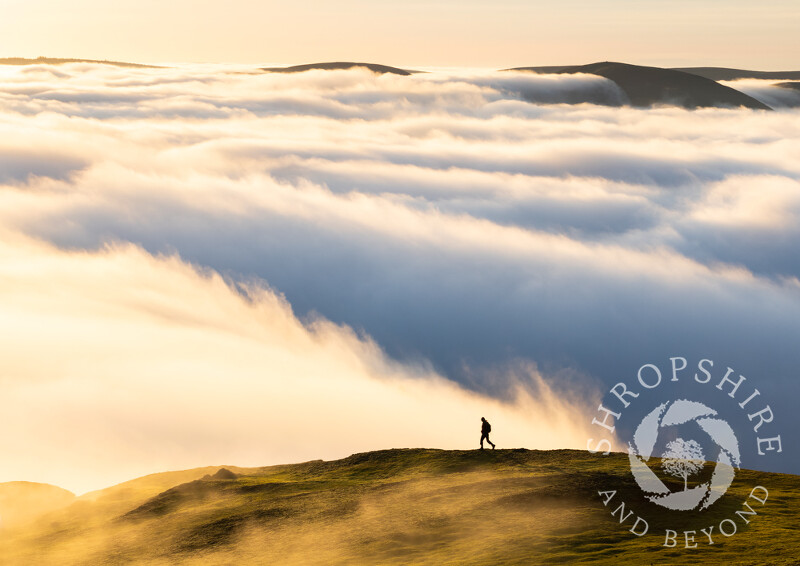 A lone walker at sunset on Caradoc, with a temperature inversion above Church Stretton, Shropshrie.